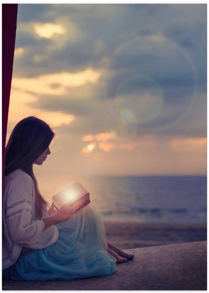 Woman sitting on a beach with illuminated book