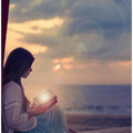 Woman sitting on a beach with illuminated book